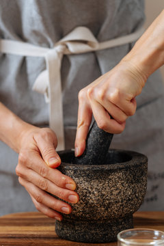 Crop woman crushing ingredients in mortar
