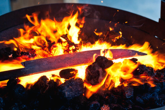 Metal blank for knife heating on blazing flame in hearth in forge