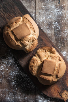 Top view of loaves of fresh bread placed on old lumber board on table covered with flour in bakery