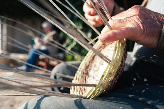 Crop senior person braiding basket