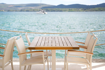 Table and chairs of an outdoor cafe on a background of the sea.