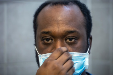  Close up Portrait of African American black male wearing a surgical mask to protect himself from contagious virus spread of Covid-19 corona virus. Healthcare has become important during quarantine 