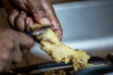 close up macro view of fresh organic ginger being cut and prepared for a health meal. the root extract is used in homemade health remedies from many cultures 