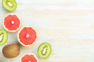 Top view of sliced citrus fruits grapefruit and kiwi on blue table.