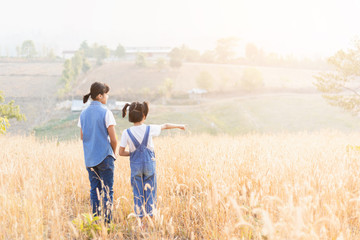Two children standing on mountain meadow at sunset