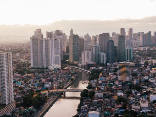 Fototapeta premium Aerial drone shot of the Skyline of Makati City in Metro Manila, Philippines while sunrise with the Pasig River in the centre of the frame