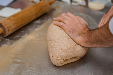 A baker kneads whole grain dough The process of making croissants in a bakery.