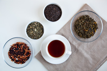 Assortment of dry tea in round bowls on a white background.