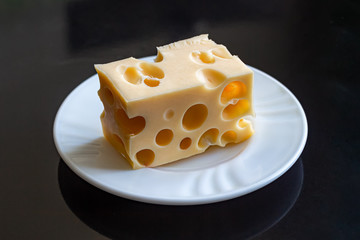 White cheese plate with a piece of Maasdam cheese, with large holes