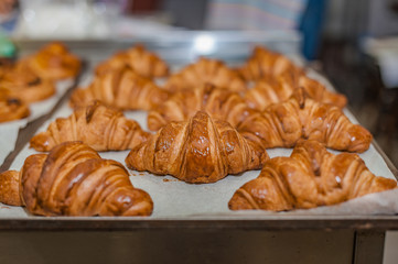 Obraz na płótnie Canvas Freshly baked croissants on a baking sheet. Commercial kitchen.