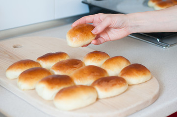 hands hold homemade patties pirozhki over wooden board with patties