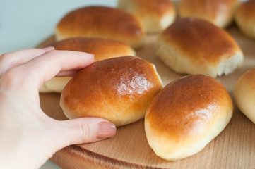 hands hold homemade patties pirozhki over round wooden board 