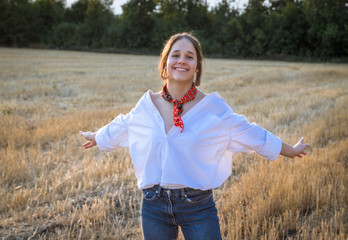 Portrait of happy girl on straw field with outstretched hands