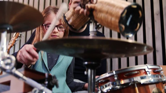 Father and daughter play percussion together.Little girl learning drums with her dad at home.Front view close up.Percussion class at home