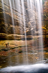 Looking out at autumn colors in a sandstone canyon from behind the misty curtain of a waterfall.