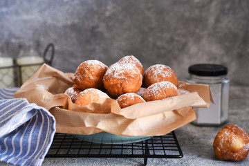 Fried donuts with icing sugar on the kitchen table.