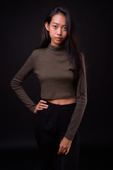 Young beautiful Asian woman against black background