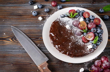 chocolate cake with fresh blueberries, red grapes and mint, sprinkled with coconut shavings,...