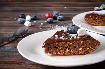 piece of chocolate cake with fresh blueberries and mint on a white saucer on a dark wooden background, dessert