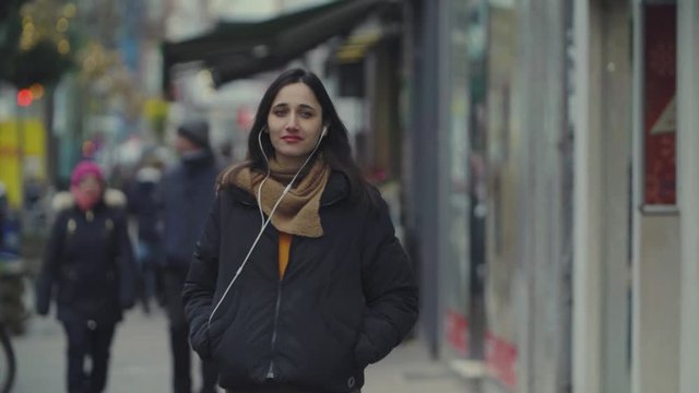 Young Woman Walking and Listening to Earphones