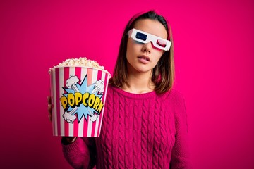 Obraz premium Young beautiful girl watching movie using 3d glasses eating box with popcorns looking sleepy and tired, exhausted for fatigue and hangover, lazy eyes in the morning.