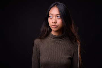 Young beautiful Asian woman against black background