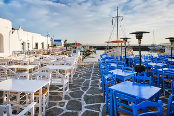 Cafe tables on quay of Naousa town port in famous tourist attraction Paros island, Greece on sunrise
