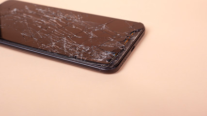 broken touchscreen black phone, smartphone, broken glass display smartphone on a beige background

