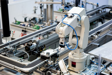 Industry 4.0 concept; artificial intelligence in smart factory prototype. Robot arm picks up the product from automated car on production line. Focus on automated car. Selective focus.