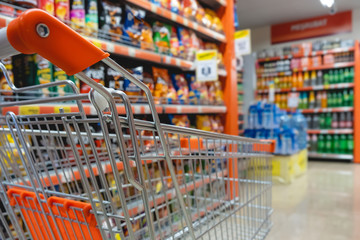 Shopping trolley cart against modern supermarket aisle blurred background