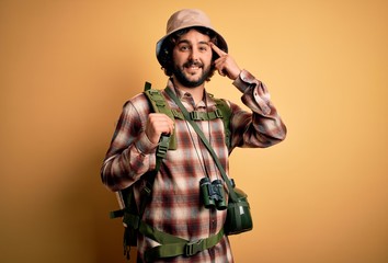 Young hiker man with curly hair and beard hiking wearing backpack and water canteen Smiling pointing to head with one finger, great idea or thought, good memory