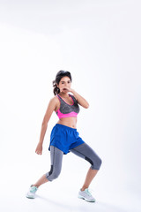 Young beautiful lady wearing sportwear,standing feet apart,raise hand up and kneel,dance workout for exercise,with happy feeling