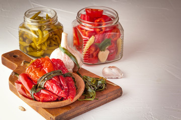 Fermented red and green hot peppers and garlic on a light wooden table. Copy space