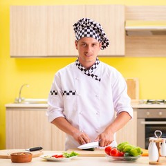 Young professional cook preparing salad at kitchen