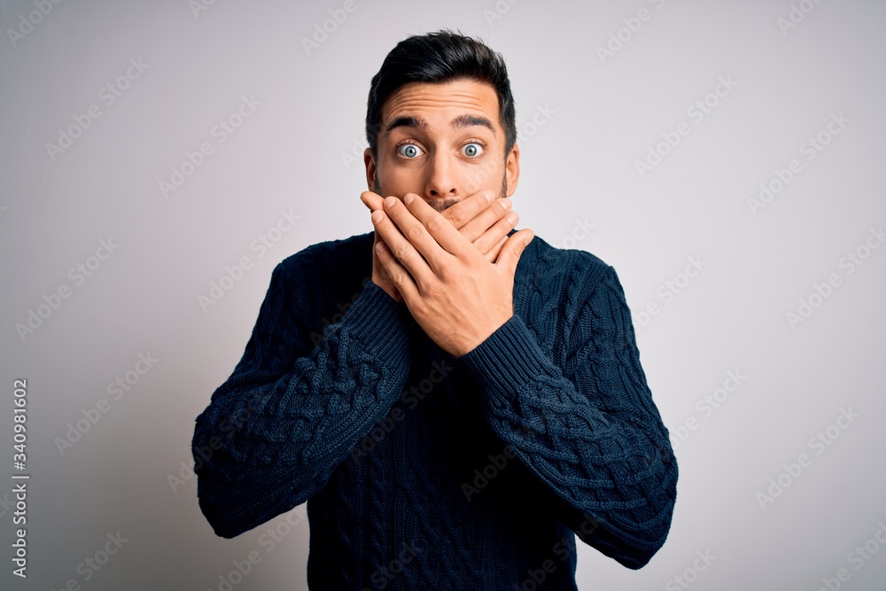 Sticker Young handsome man with beard wearing casual sweater standing over white background shocked covering mouth with hands for mistake. Secret concept.