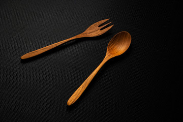 Wood spoon and fork put on black canvas background