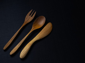 Wood spoon,fork and butter knife put on black canvas background