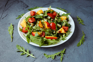 Summer colorful healthy salad made of spinach, avocado, nectarine, chia seeds, aragula, cherry tomatoes. Salad is sprinkled with olive oil and balsamic vinegar.