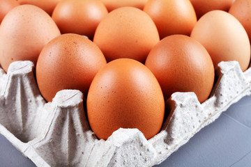 Chicken eggs in a paper tray on a gray background, close-up