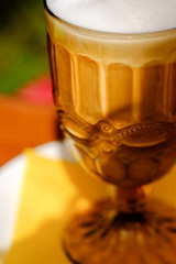 Fresh morning latte in a glass with foam on a blurry green background. Selective focus