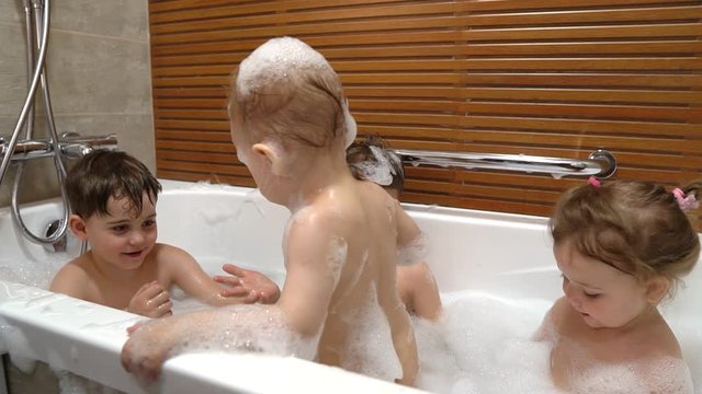 four children, brothers and sisters bathe in a bath with foam