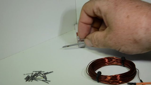 Iron nail is seen to be non magnetic, then it is magnetized by a bar magnet in the background, the nail can now lift some of the small nails. The nail is held into an AC coil it looses magnetism.