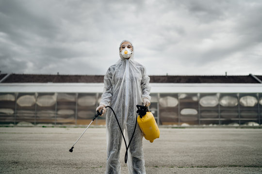 Sanitation Worker In Hazmat Protection Suit  And N95 Mask With Chemical Decontamination Sprayer Tank.Disinfecting Streets And Public Areas To Stop COVID-19 Spread.Coronavirus Disinfection Concept