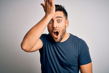 Young handsome man wearing casual t-shirt standing over isolated white background surprised with hand on head for mistake, remember error. Forgot, bad memory concept.