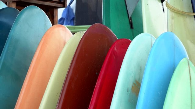 Set of different color surf boards in a stack by ocean. Surfing boards for rent. Surf lessons on Batu Bolong beach, Bali, Indonesia.