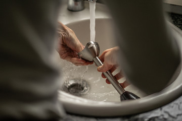 Obraz premium Cleaning a mixer in the dishwasher. A person cleaning a mixer in the dishwasher at home.