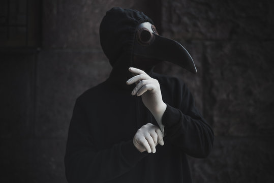 Modern stylized plague doctor in leather mask wearing medical latex gloves. Epidemia protection concept