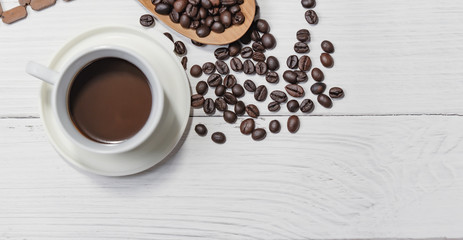 Cup of black coffee  and coffee beans good essentials on white wooden background. Top view.