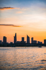 Obraz premium River city view landscape at twilight sunset. Boat on river with tranquil water. Hochiminh city Saigon vietnam cityscape building with Bitexco tower