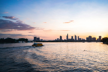 Fototapeta na wymiar River city view landscape at twilight sunset. Boat on river with tranquil water. Hochiminh city Saigon vietnam cityscape building with Bitexco tower